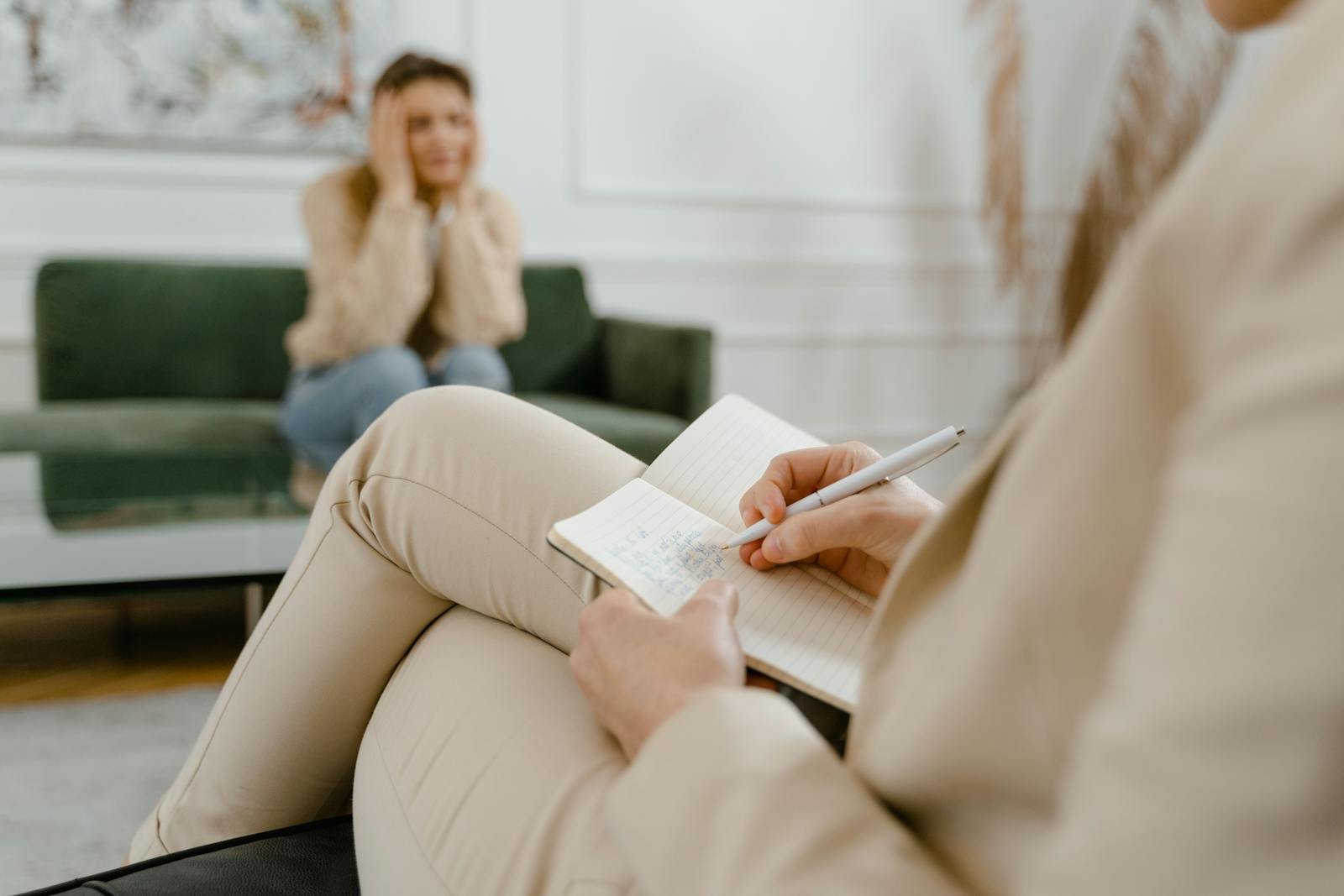 A therapist taking notes during a consultation with a patient, focusing on mental health.